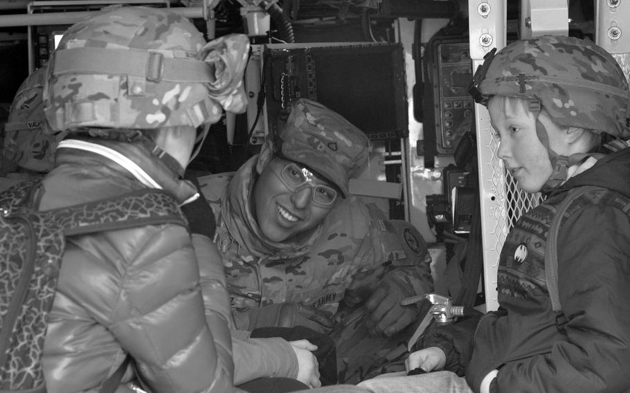 A soldier smiles at two children.